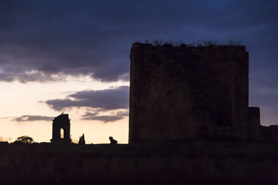 Silhouette of old building against sky at sunset