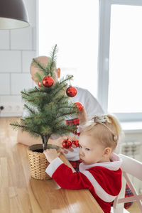 Cute girl playing with christmas tree at home