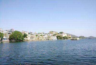Buildings by sea against clear sky