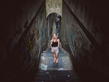 Full length portrait of woman standing in abandoned building