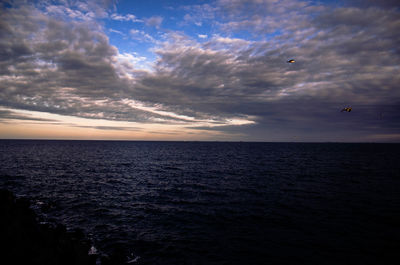 Scenic view of sea against cloudy sky during sunset