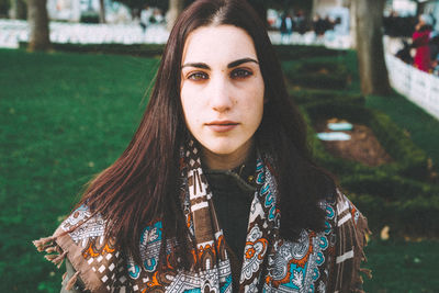 Portrait of young woman with scarf standing in park