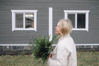 Young woman christmas tree bouquet, standing outdoors