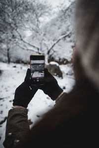 Reflection of person photographing on snow covered camera