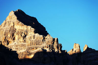 Low angle view of rocky mountains against clear blue sky