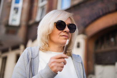 Portrait of woman wearing sunglasses while standing in city