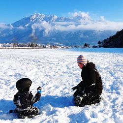 Mother and son kneeling on snow covered land