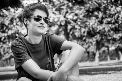 Portrait of young man wearing sunglasses sitting at park