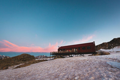 Built structure on snowcapped mountain against blue sky