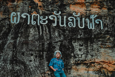 Portrait of woman standing against graffiti wall