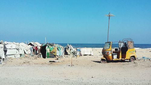 Abandoned rickshaw at beach against clear blue sky