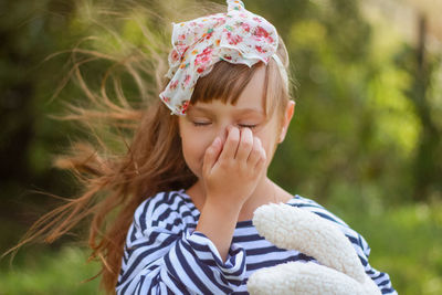 Beautiful little girl in striped oversized shirt with hair bow in the field at summer