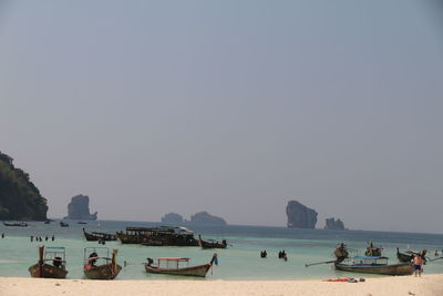 Tourists on beach against clear sky