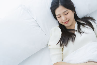 Smiling young woman sleeping on bed