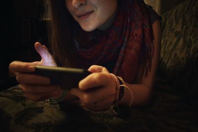 Midsection of woman using mobile phone while resting on sofa at home