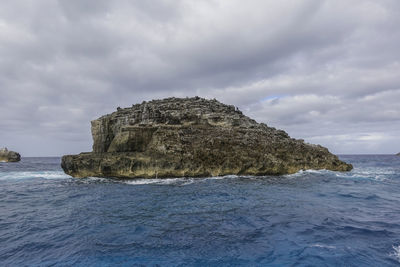 Rock formation on sea shore against sky
