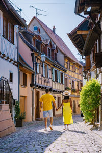 Rear view of people walking on street amidst buildings