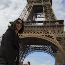 Low angle view of happy woman wearing sunglasses standing against eiffel tower