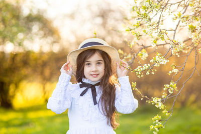 Portrait of young woman standing against trees