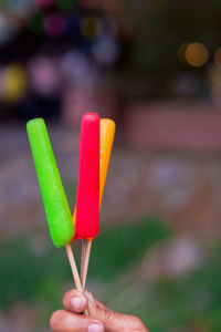 Close-up of hand holding colorful flavored ice outdoors