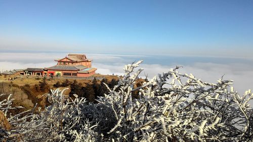 Traditional building by sea against sky during winter