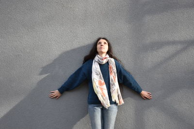 Thoughtful woman standing against gray wall