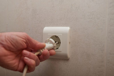 Close-up of hand holding camera against wall