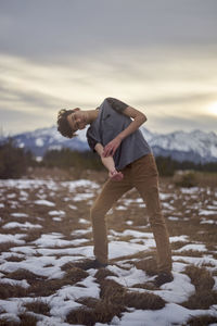 Portrait of young man with head cocked standing on field during winter