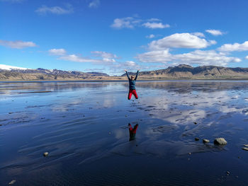 Woman jumping at beach against sky