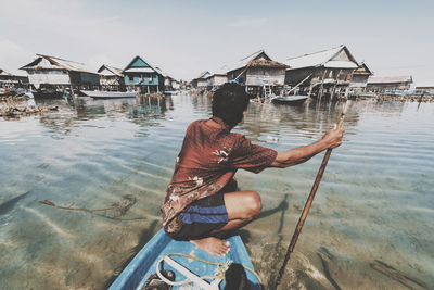 Rear view of man by sea against building