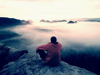 Rear view of man sitting on mountain