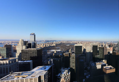 Modern buildings in city against clear blue sky