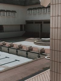 Empty chairs and tables in swimming pool against buildings in city