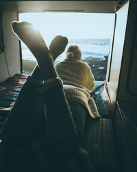 Rear view of woman lying by window at home