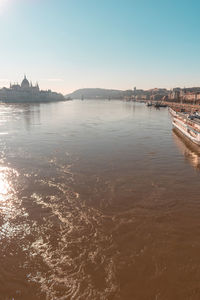 Scenic view of river by buildings against sky