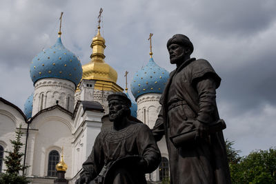 Statues and russian orthodox church against cloudy sky