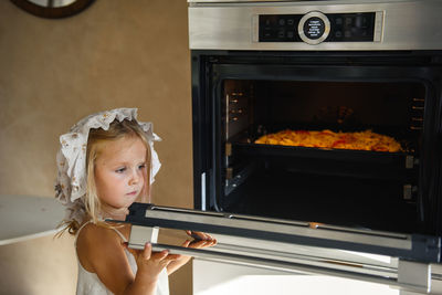 Little girl cooking pizza in the kitchen