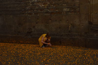 Woman sitting on stone wall