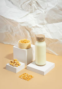 Vegetable pea milk in a bottle and chickpeas in bowl on white podium.isometric diagonal projection