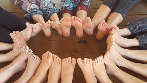 High angle view of people with barefeet sitting on hardwood floor