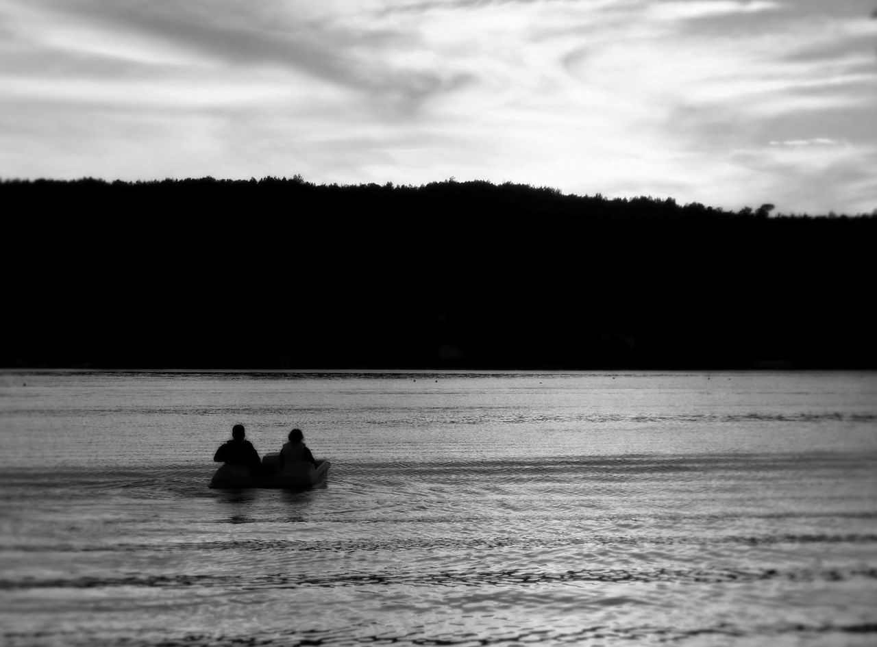 SILHOUETTE MEN IN BOAT AGAINST SEA