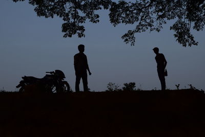 Silhouette of men standing by tree against sky