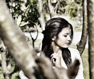 Portrait of young woman looking at tree