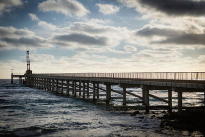 Pier over sea against sky during sunset