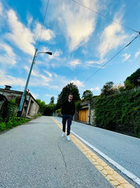 Rear view of man walking on road against sky