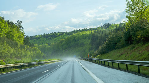 Road amidst trees against sky