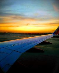 Airplane on runway against sky during sunset