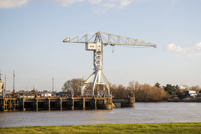 Cranes by river against sky