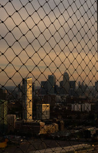 Close-up of chainlink fence against sky during sunset