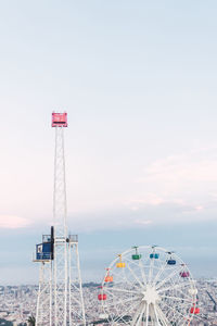 Aerial view of ferris wheel with colorful cabins in tibidabo amusement park located in collserola ridge in barcelona against cloudy sky